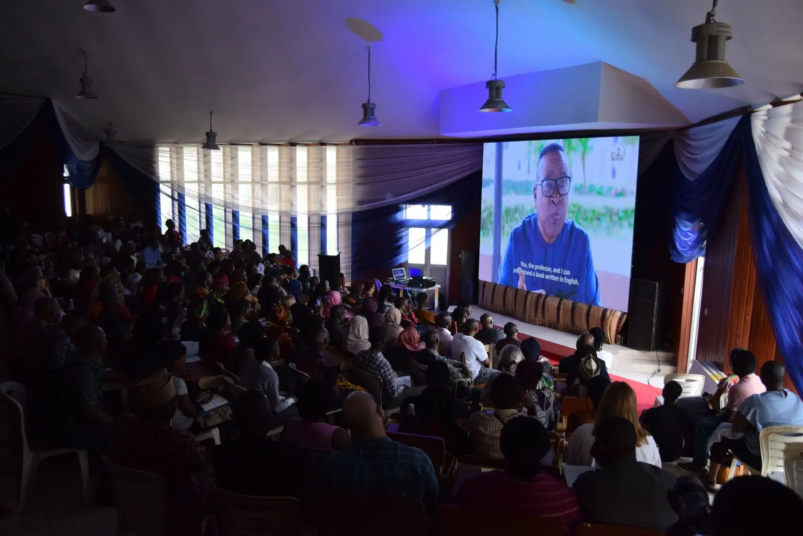 A full auditorium of conference attendees watching a screening in Lagos